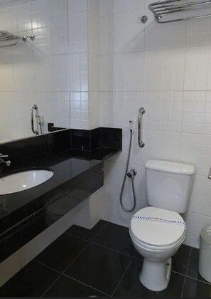 A bathroom with a black countertop, white sink, and a white toilet. - Hotel Domani (Guarulhos)