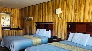 A room with two beds, wooden walls, a wooden floor, a mirror, a lamp, and a small table. - Country Inn Motel (Licking)
