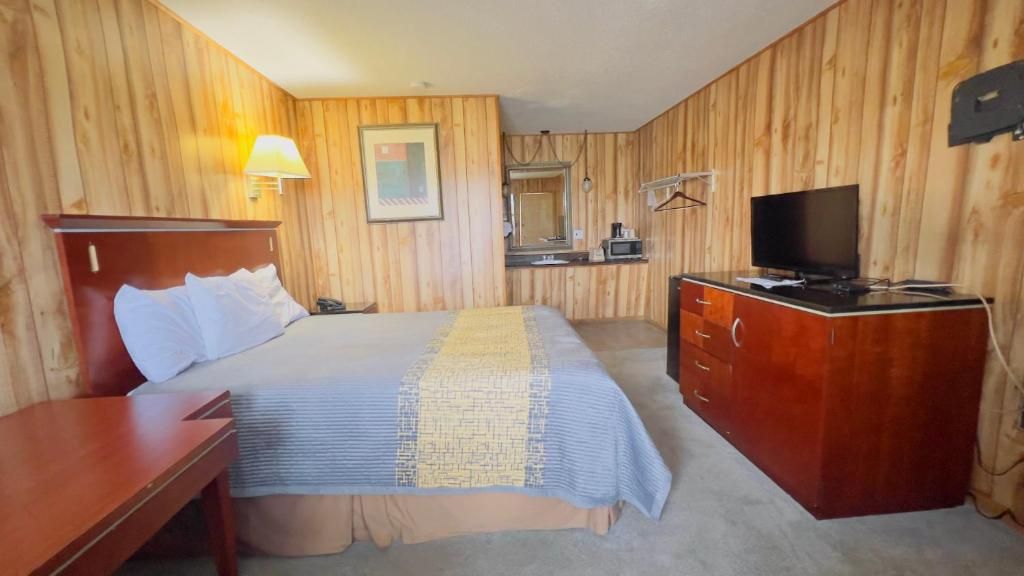 A hotel room with a bed, a desk, a television, and a mirror.