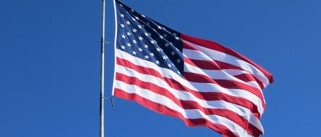 An American flag on a flagpole against a clear blue sky.
