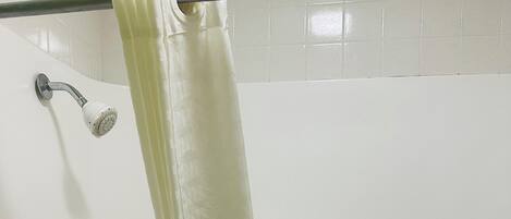 Un baño con bañera, ducha y barra para cortina.