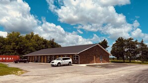 A two-story brick building with a flat roof and a parking lot in front. - Country Inn Motel (Licking)