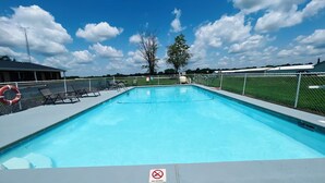 A swimming pool with a no diving sign, surrounded by a fence, with lounge chairs and a lifebuoy on the left. - Country Inn Motel (Licking)