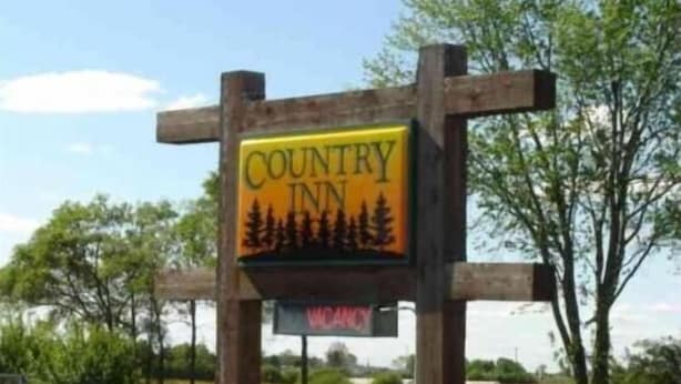 A wooden sign with the text "COUNTRY INN" and a forest silhouette. - Country Inn Motel (Licking)