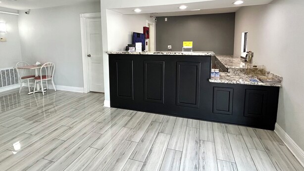 A kitchen with a marble countertop, black cabinets, and a dining area with a chair.