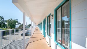 A covered corridor with white walls and teal trim, leading to a parking area.