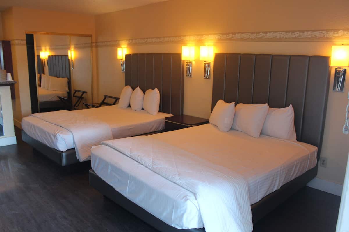 Habitación de hotel con dos camas, un escritorio y una silla.