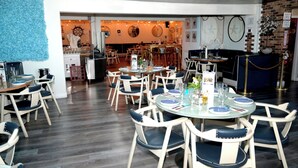 Ein Restaurant mit runden Tischen, Stühlen und einer Ziegelwand.