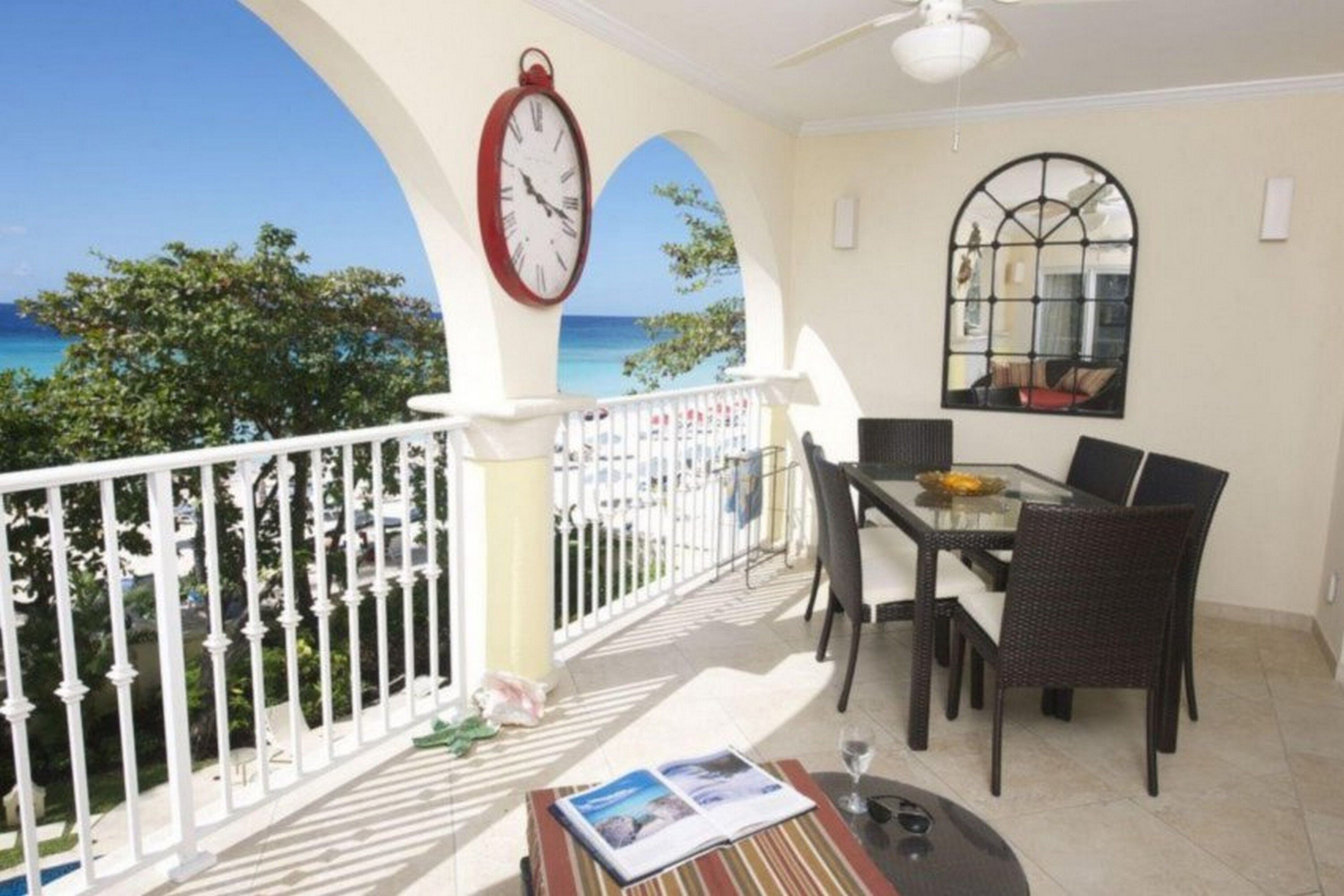 Un balcon avec une table à manger, des chaises et une horloge.