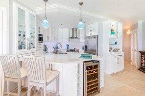 A modern kitchen with white cabinetry, a central island, stainless steel appliances, and pendant lighting. - Sapphire Beach Condominiums by Blue Sky Luxury (St. Lawrence Gap)