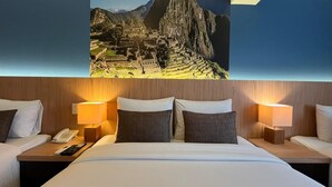 Habitación de hotel con una cama grande, dos mesitas de noche, un teléfono y un cuadro colgado en la pared de Machu Picchu.