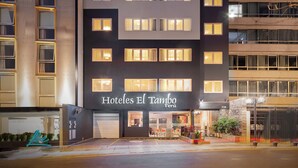 Un moderno edificio de hotel con varios pisos y ventanas iluminadas, que muestra una entrada visible y señalización.