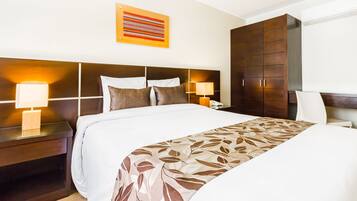 Habitación de hotel con una cama grande, dos mesitas de noche con lámparas, un armario y una obra de arte en la pared.