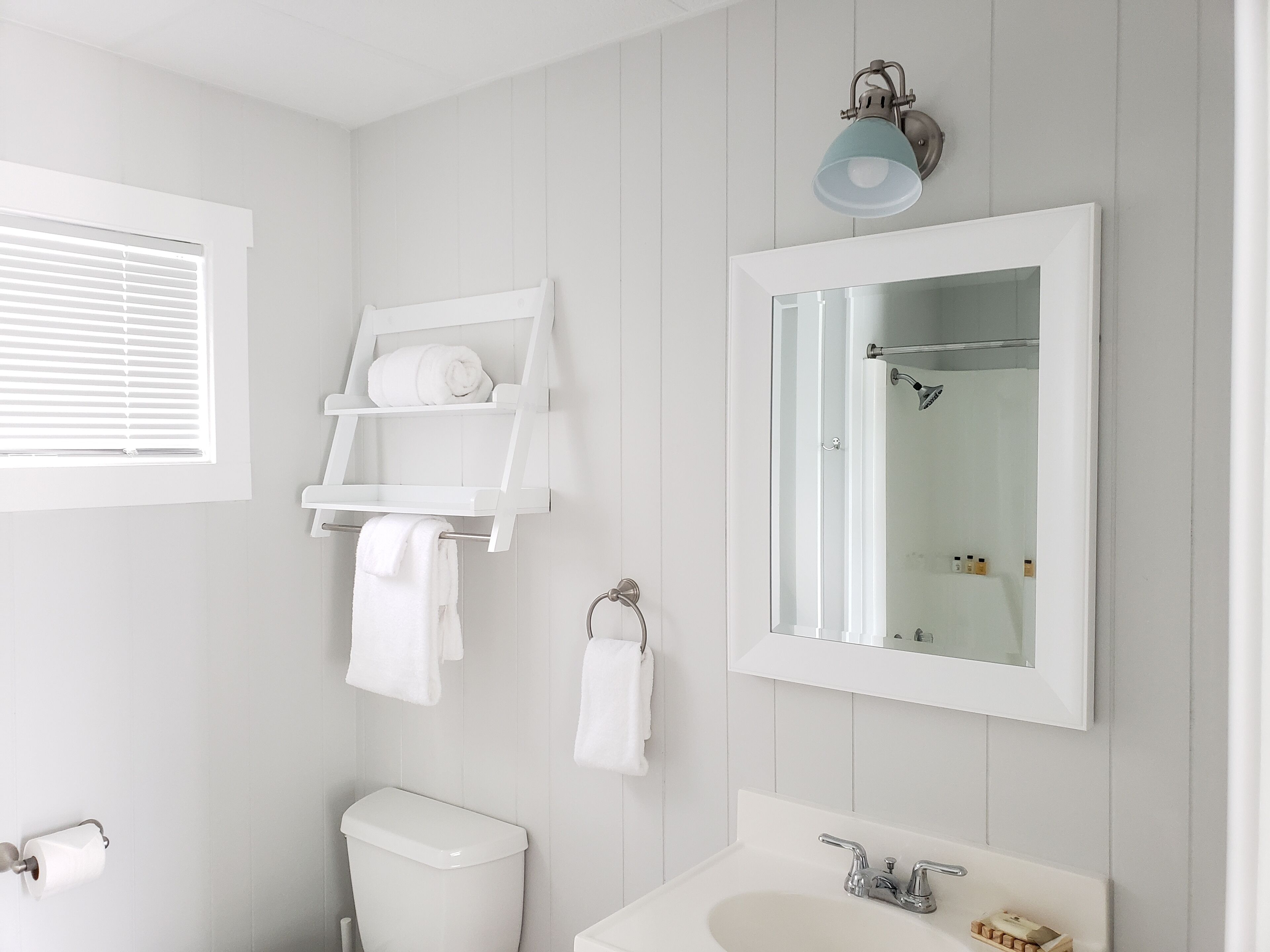 A bathroom with a toilet, sink, towel rack, and a mirror.