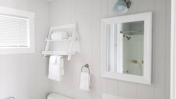 Et badeværelse med toilet, vask, bøjle til håndklæder og et spejl.