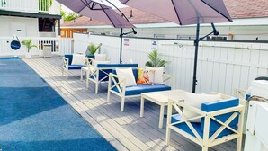 Una terraza con mobiliario exterior, sombrillas y una piscina.
