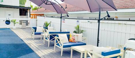 Una terraza con mobiliario exterior, sombrillas y una piscina.