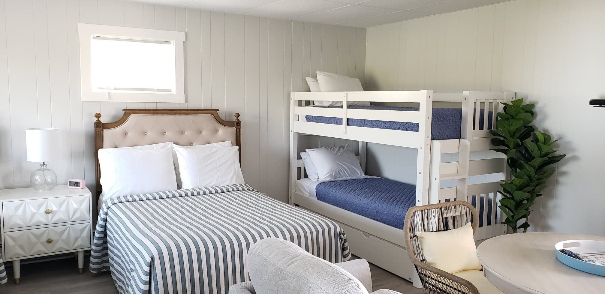 A bedroom with a bed, a nightstand, a chair, and a bunk bed.