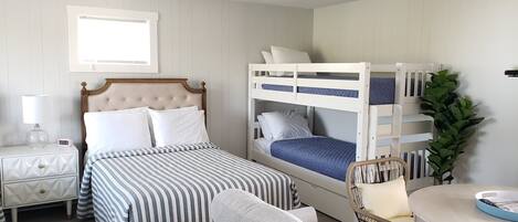 A bedroom with a bed, a nightstand, a chair, and a bunk bed.