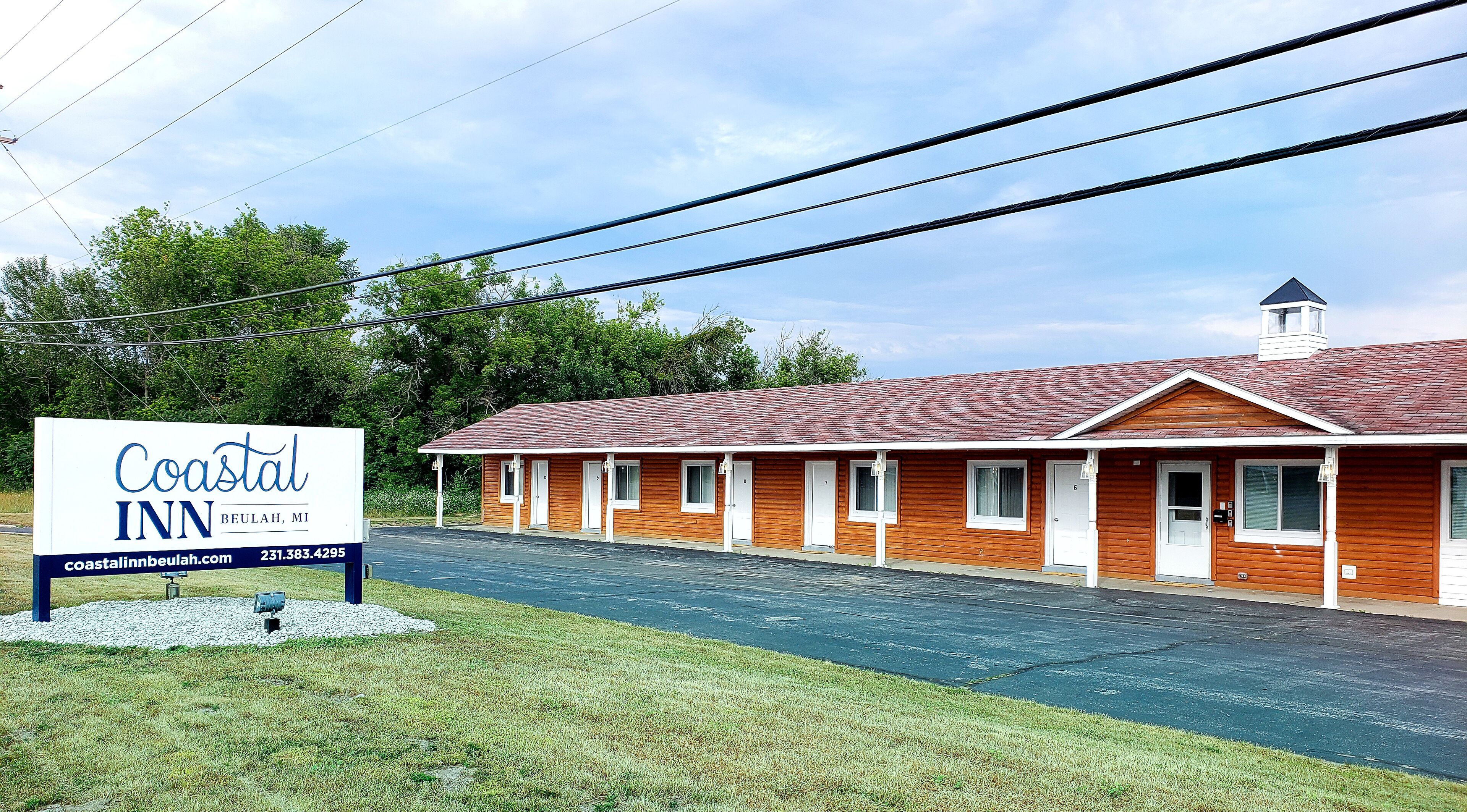 Un motel de bord de mer, avec une enseigne, une façade en bois et un ciel dégagé.