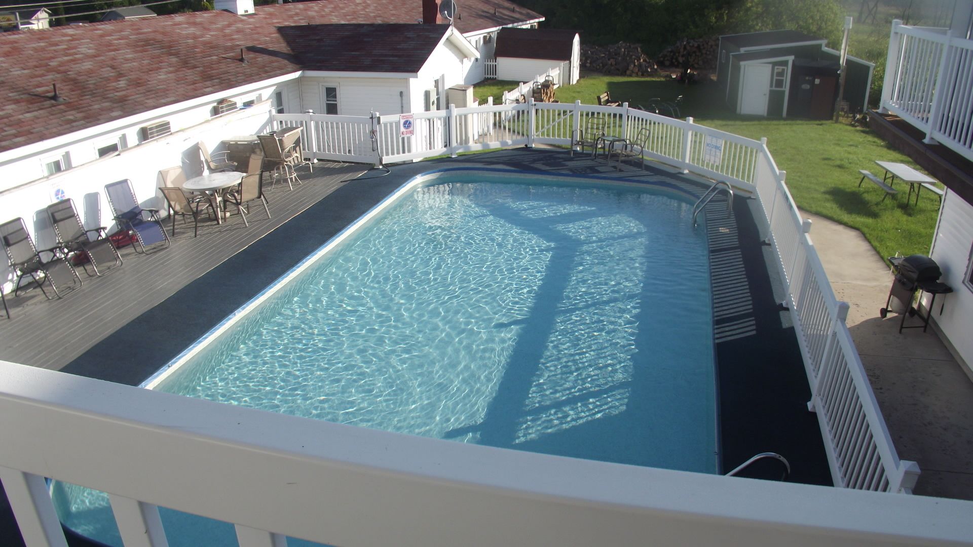 A rectangular swimming pool with a white deck and a white fence surrounding it.