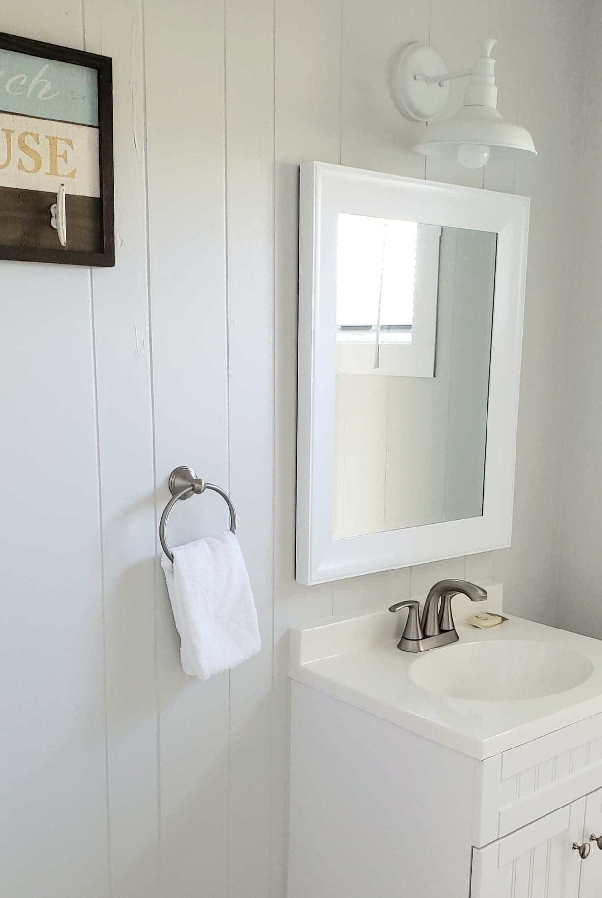 Une salle de bain avec un lavabo blanc, un miroir et un porte-serviettes.