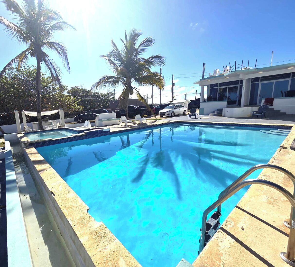 Ein Swimmingpool mit Liegestühlen und Palmen.