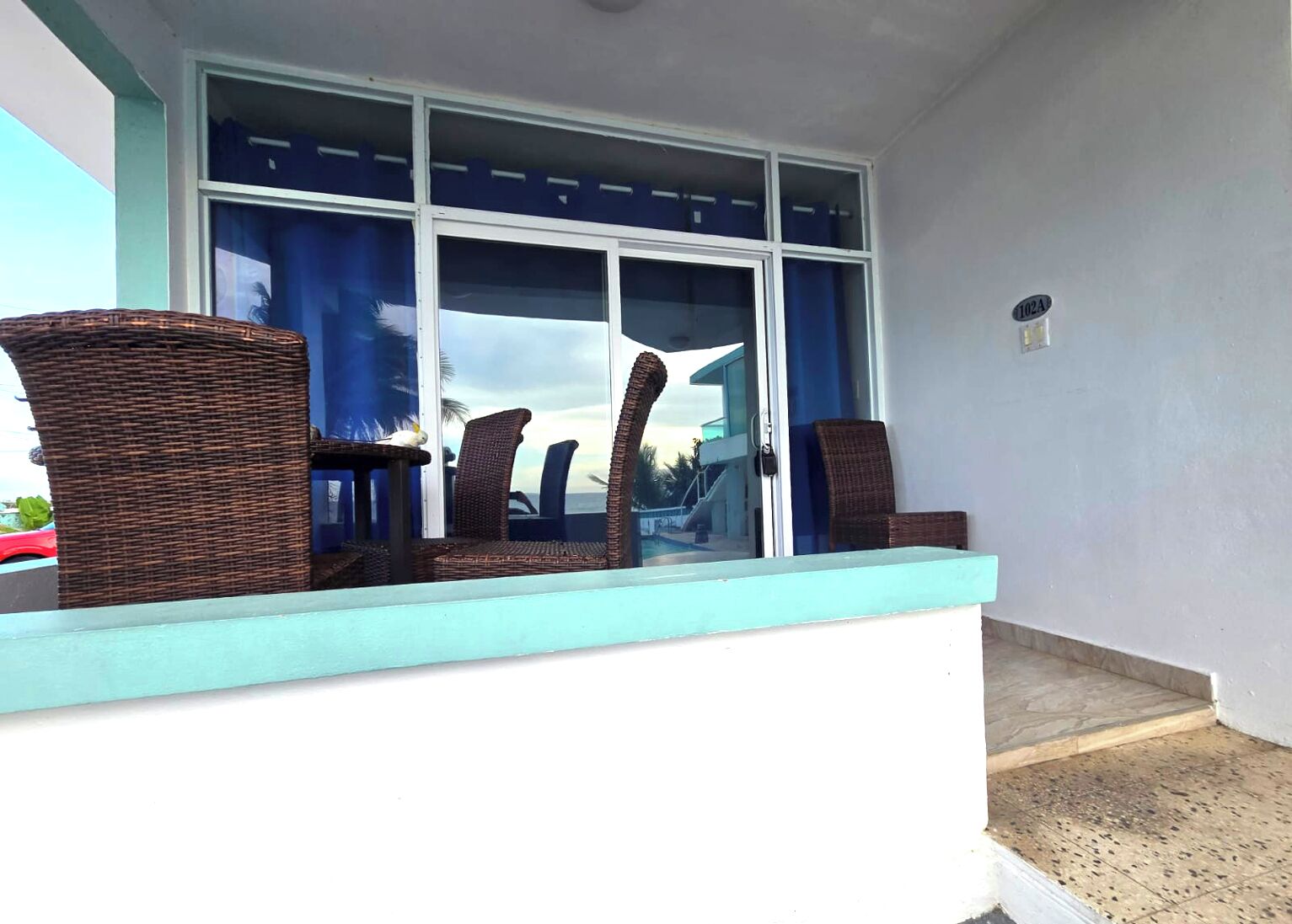 A balcony with wicker furniture and a view of the ocean.
