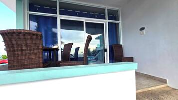 A balcony with wicker furniture and a view of the ocean.