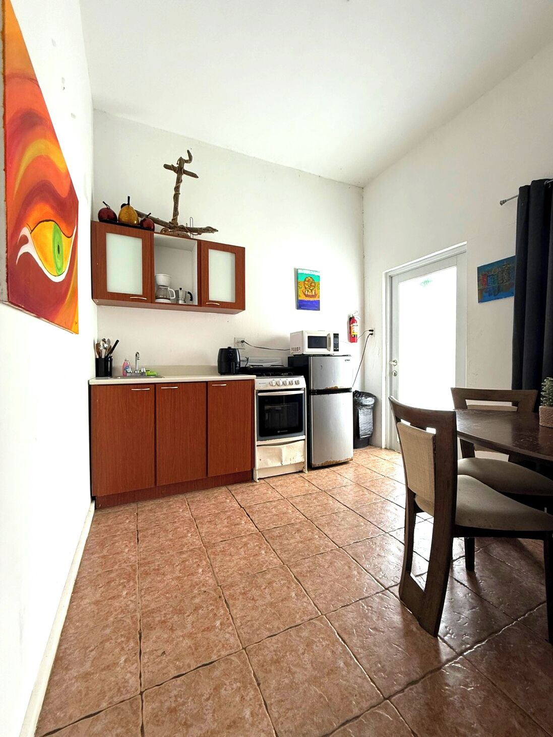 A compact kitchen with wooden cabinets, a microwave, a stove, and a refrigerator.