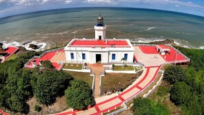 A lighthouse with a red roof, white walls, and a flagpole.