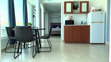 A compact kitchen with a dining area, a microwave, and a refrigerator.