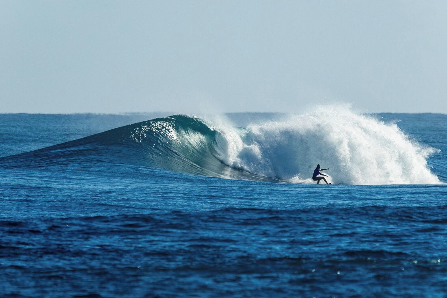 A surfer riding a large wave in the ocean.