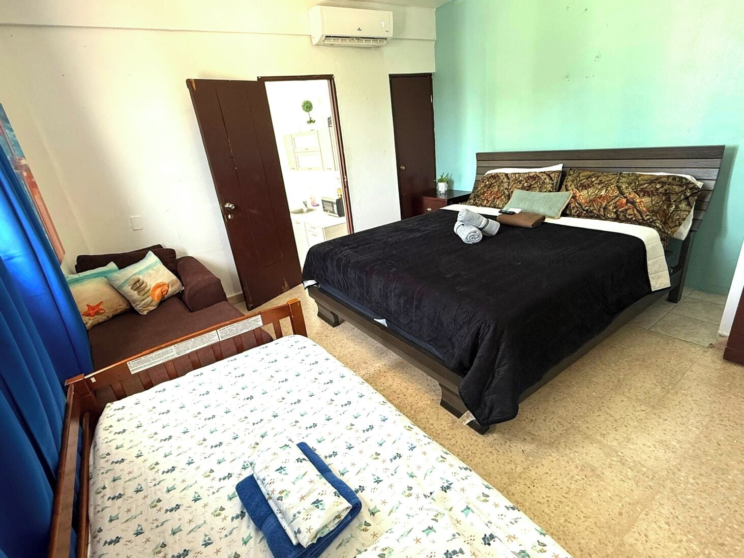 A bedroom with a large bed, a smaller bed, a sofa, and a desk.