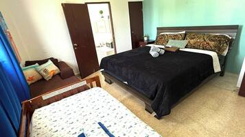 A bedroom with a large bed, a smaller bed, a sofa, and a desk.
