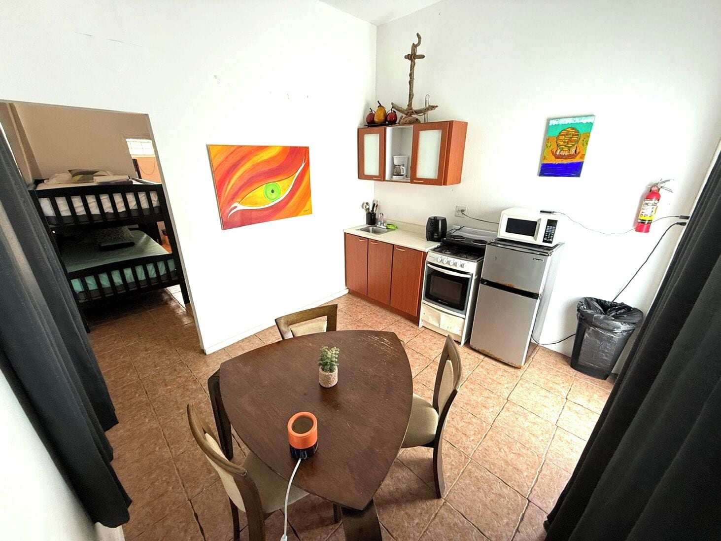 A compact kitchen with a dining area, a bunk bed, and a painting on the wall.