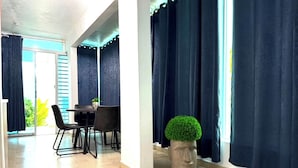 A modern room with a dining area, a potted plant, and a view through large windows.