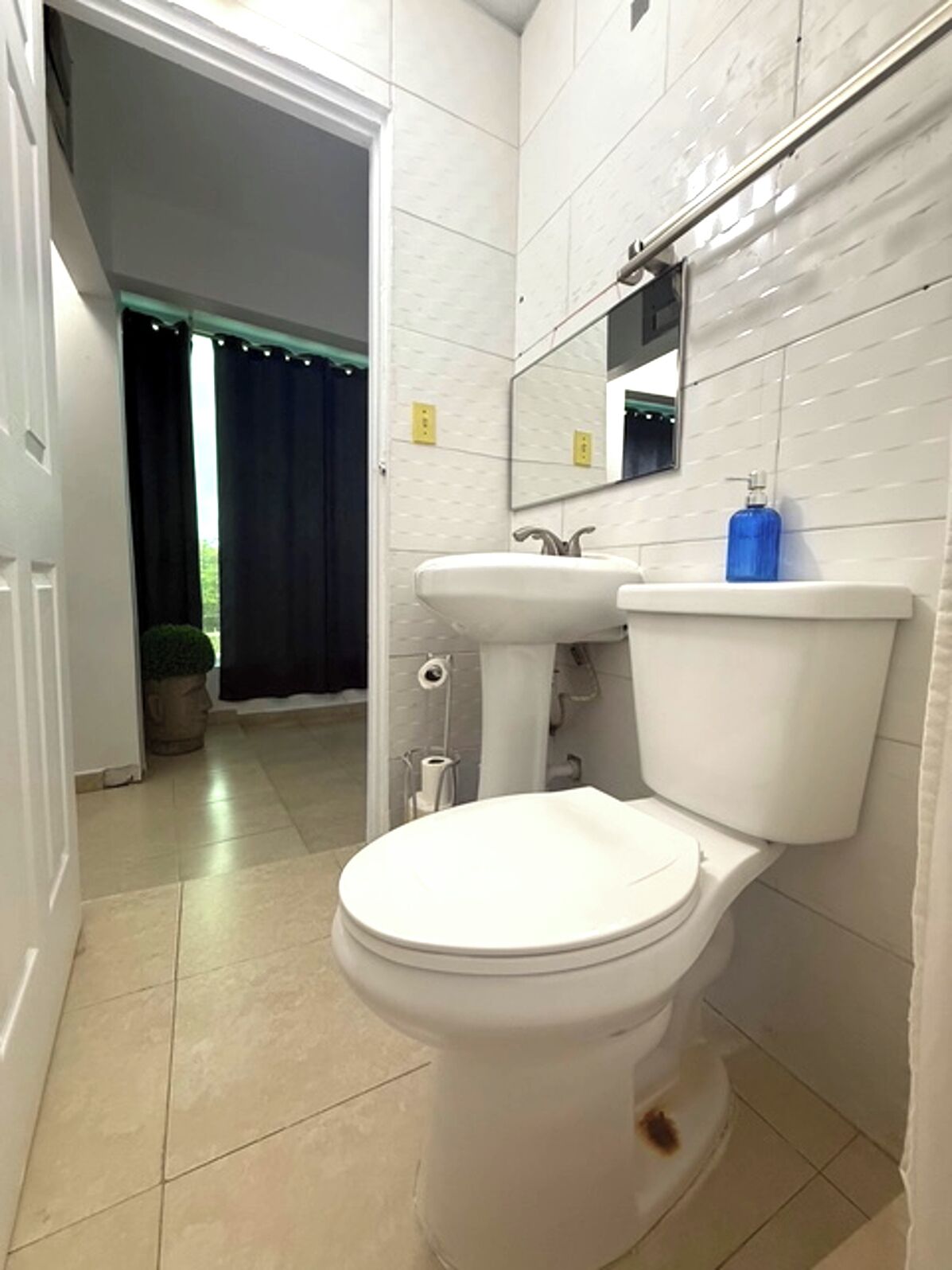 Un baño con inodoro blanco, lavamanos y espejo.