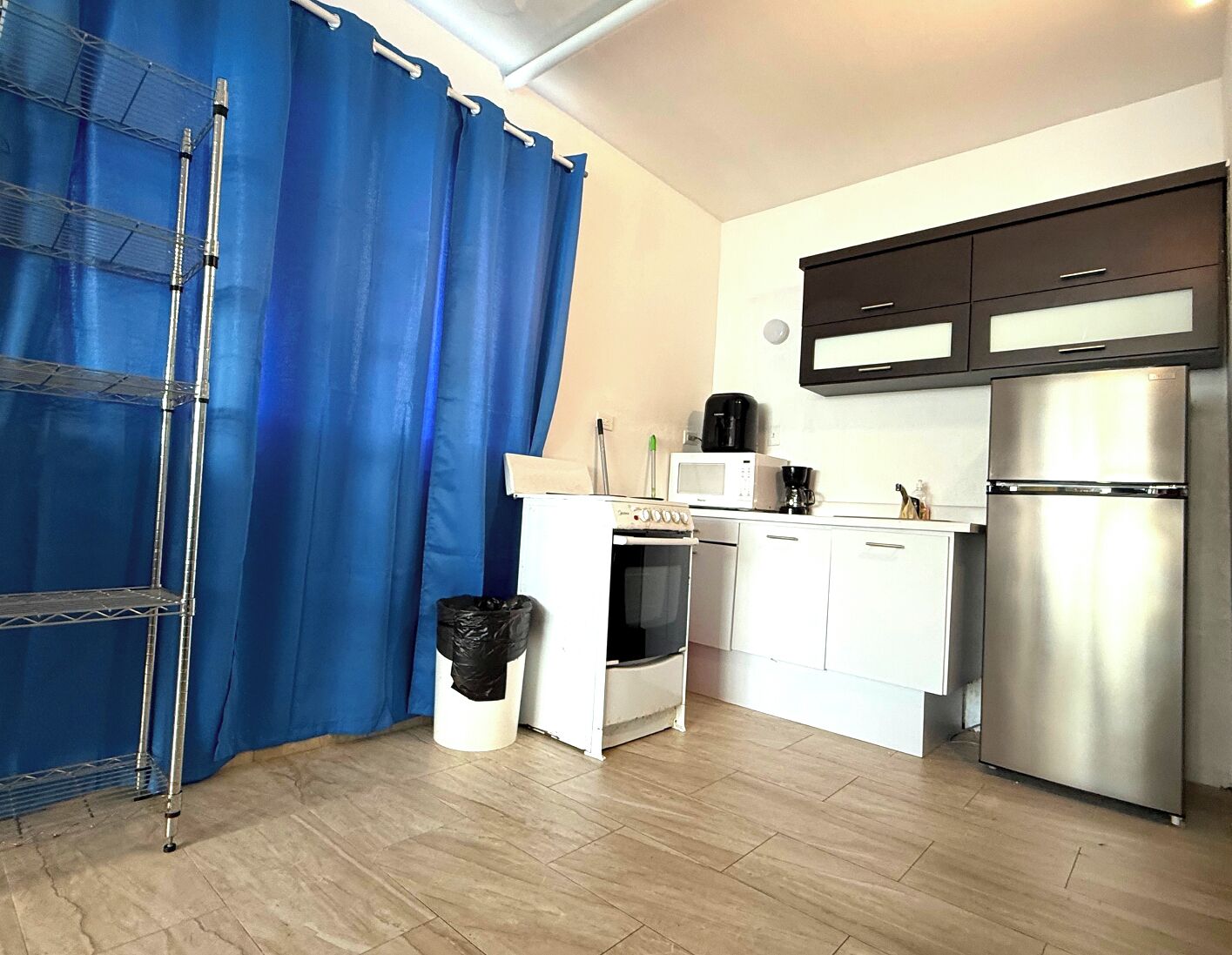 A modern kitchen with white cabinets, a stainless steel refrigerator, a microwave, and an oven.
