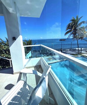A modern infinity pool with a clear view of the ocean and palm trees. - Ventana al Atlantico at Arecibo 681 Ocean Drive (Arecibo)