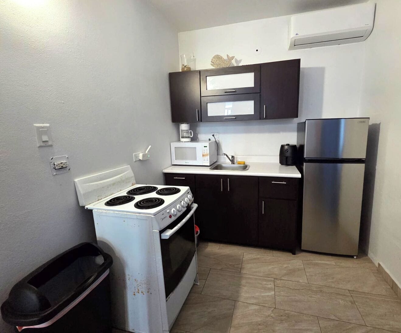 Una cocina compacta con estufa, microondas y refrigerador.