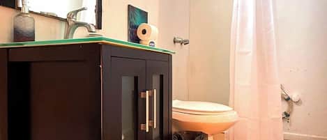 A bathroom with a toilet, sink, and shower.