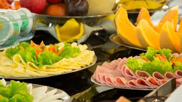 Un buffet proposant une variété de plats, notamment des nouilles, des viandes en tranches et des légumes frais.