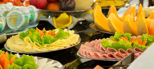 A buffet with various food items including noodles, sliced meats, and fresh vegetables.