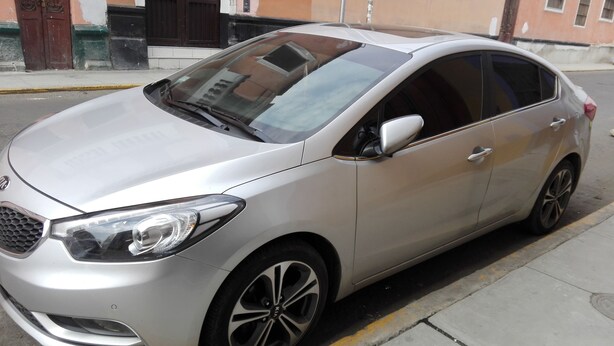 Un sedán plateado estacionado en una calle de la ciudad.