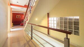 Un interior moderno con una escalera, una pared roja con un cuadro y una pared de bloques de vidrio.