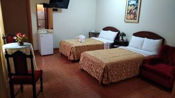 A hotel room with two beds, a TV, a small table with a vase of flowers, a red chair, and a painting on the wall.