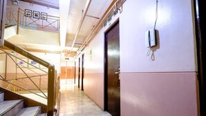 Een hotelgang met een trap, een telefoon en een nooduitgang.
