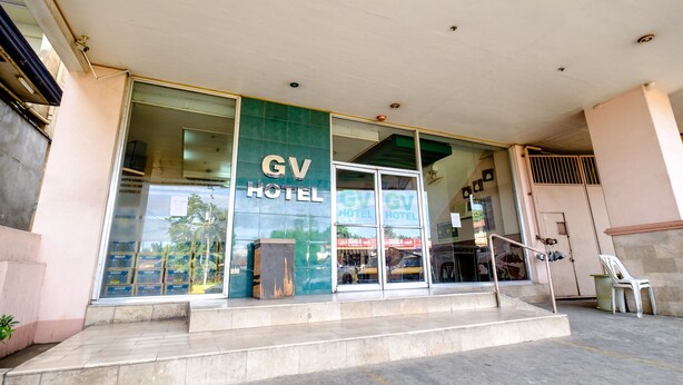 Een hotelentree met een opvallend 'GV HOTEL' bord, een glazen gevel en een trap naar de ingang.