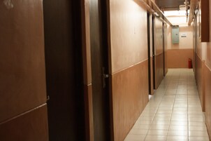 Un pasillo con puertas a ambos lados, suelo de baldosas y un extintor a la derecha.